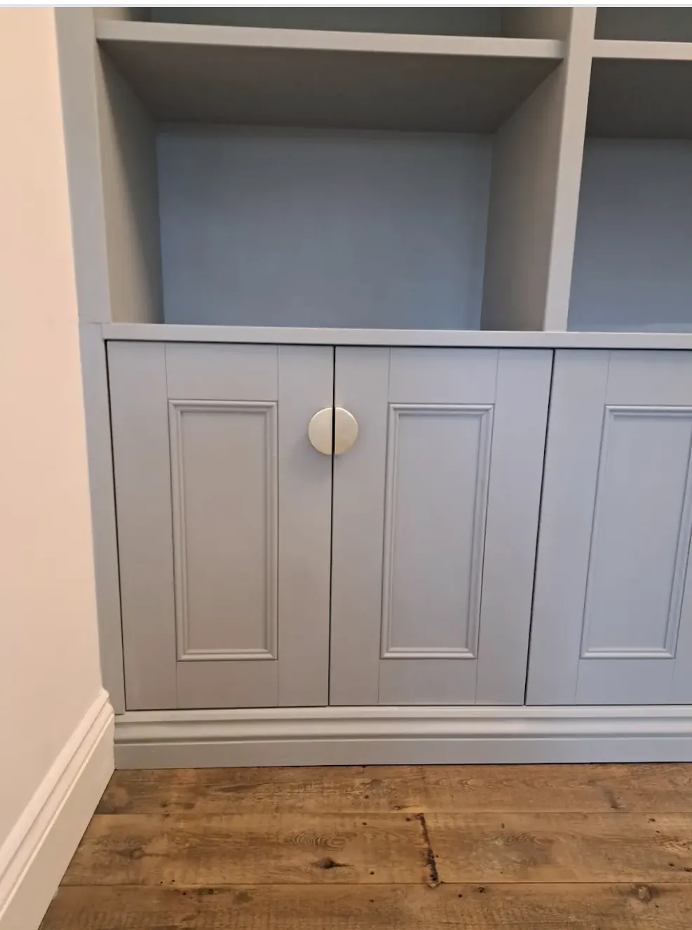 Close detail of raised and fielded cupboard doors with a brass knob, scribed to skirting