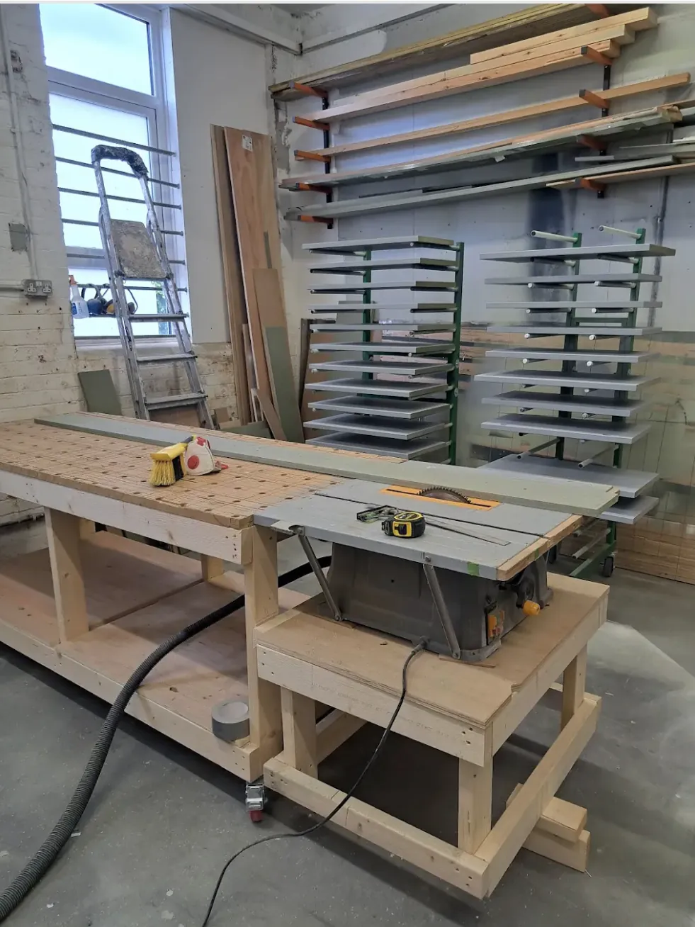 Carpentry workshop with a bench, table saw and racks of cabinet doors drying